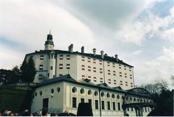 Ambras Castle in Innsbruck, white facade with red windows under cloudy sky