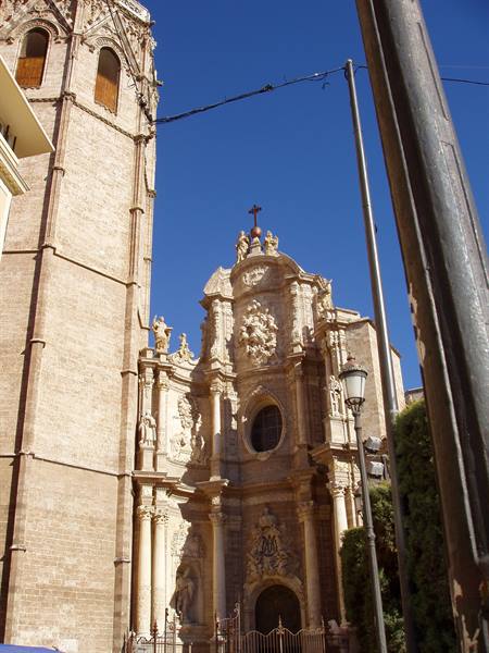 Baroque stone facade and Miguelete gothic tower, Valencia, against deep blue sky