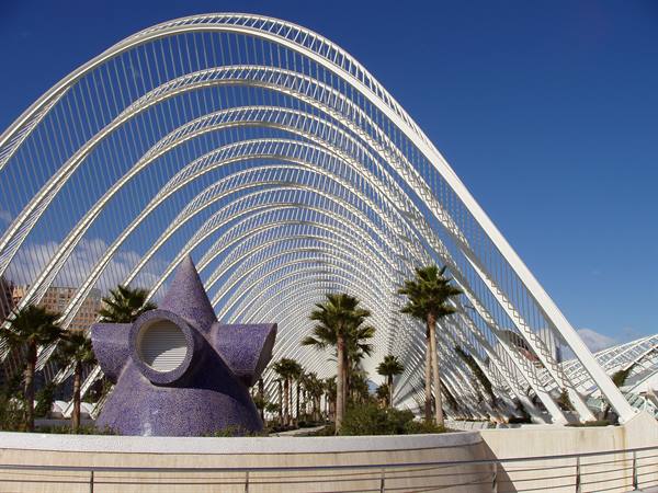 White arches of L'Umbracle in Valencia with purple mosaic sculpture and palm trees