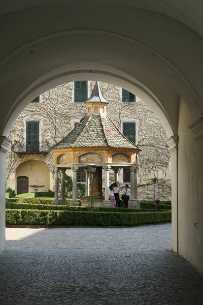 Frescoed octagonal pavilion seen through an arch, castle garden