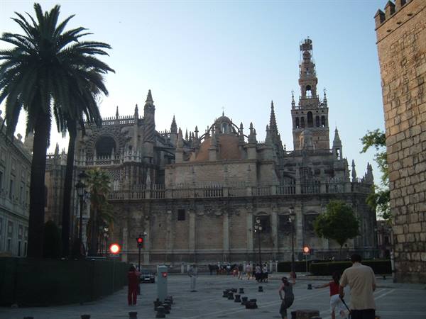 Seville Cathedral and the Giralda tower at dusk, people strolling outside