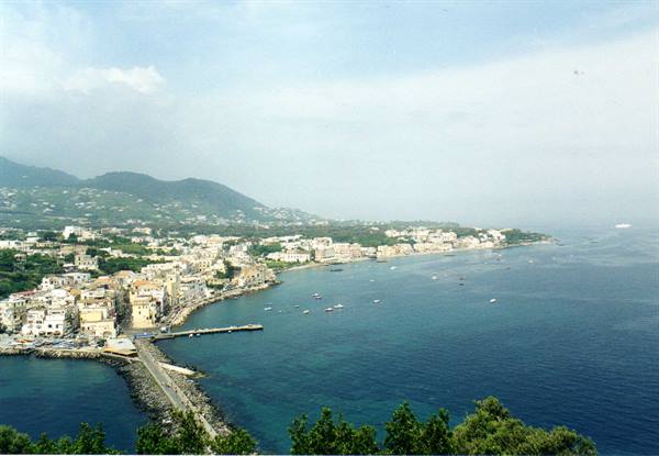 The harbor of Ischia with boats, pier and houses overlooking the blue sea