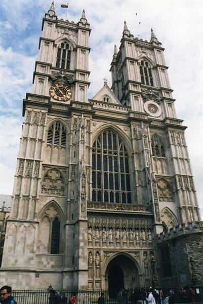 Westminster Abbey Gothic stone facade, twin towers, golden clock, visitors below