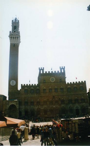 Tourists in Siena's Piazza del Campo beneath the Palazzo Pubblico and Torre del Mangia