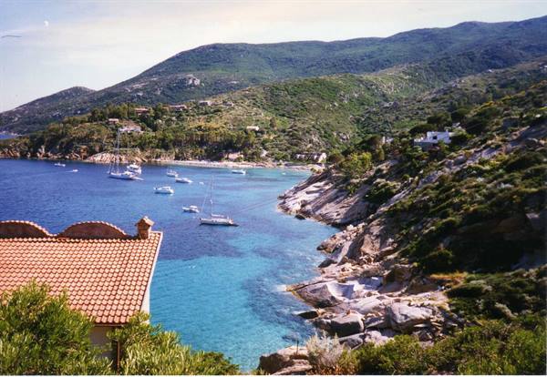 Bay with anchored yachts, granite rocks and terracotta roofs, Giglio Island