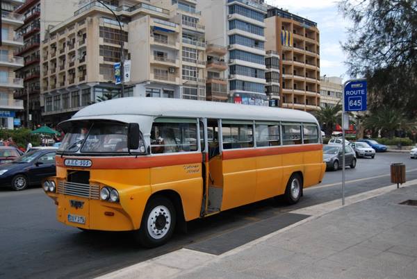 Old yellow Maltese bus driving along the Sliema waterfront