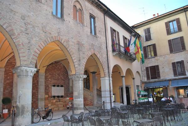 Medieval arcades of Palazzo dell'Arengo on Piazza Cavour in Rimini, outdoor café tables