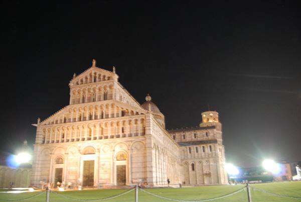 Pisa Cathedral lit up at night, white marble, green lawn in front