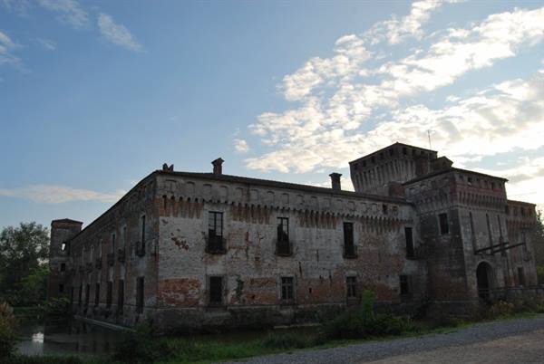 Ancient brick castle with moat under cloudy sky