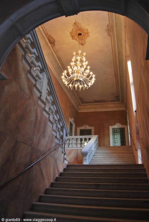 Pink marble staircase with crystal chandelier beneath an arch