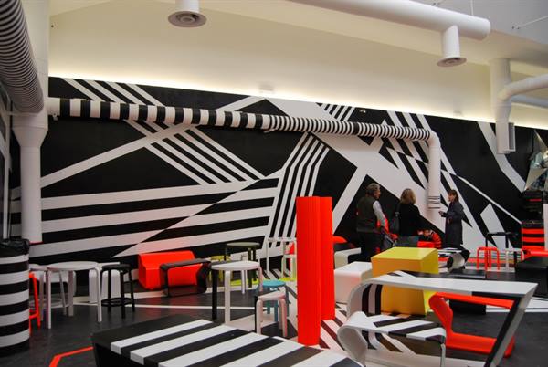 Visitors in lounge room with red furniture and black-and-white murals