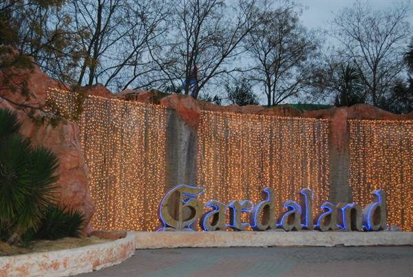 Illuminated Gardaland sign in front of golden light waterfall on rocky wall