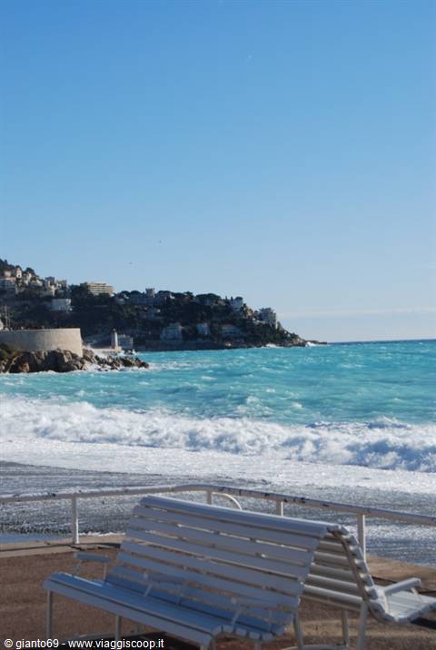 Empty white bench facing turquoise waves on the seafront of Nice