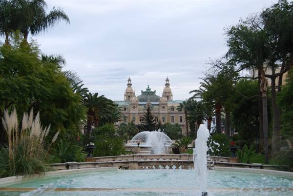Fountains among palm trees in front of Monte-Carlo Casino under cloudy sky
