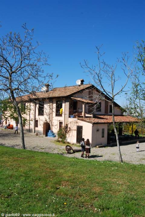 Farmhouse with terracotta roofs, people strolling under a clear blue sky