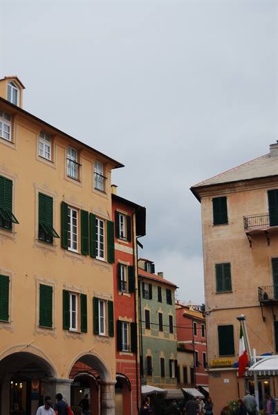 Colorful buildings with green shutters, arcades and Italian flag in a square