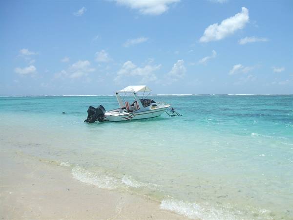 White motorboat with outboard engine anchored between the sand and turquoise water