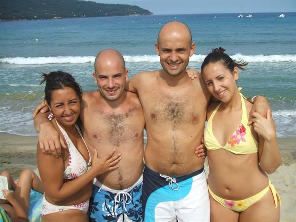 Two men and two women in swimwear hugging on the beach by the sea