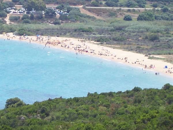 sandy beach with bathers and umbrellas overlooking turquoise sea