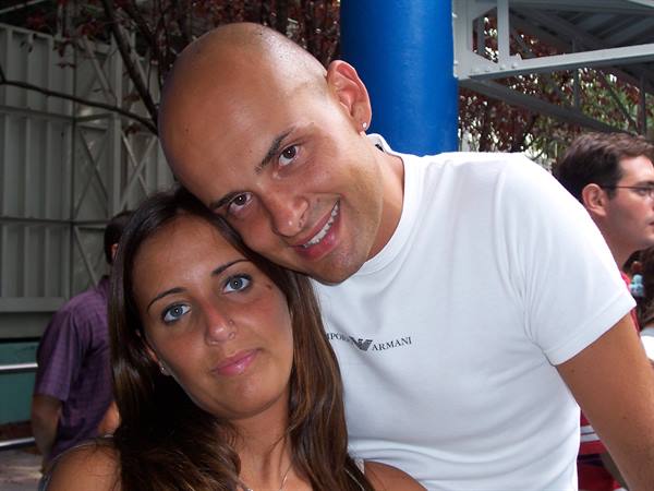 smiling man in white t-shirt next to a woman among blue metal structures