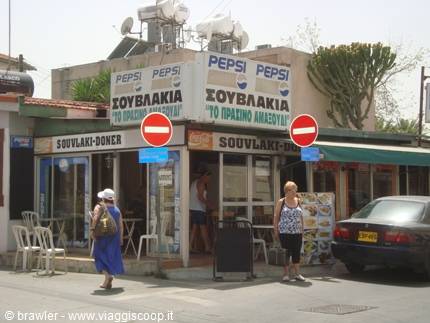 Tourists walk past a souvlaki shop with Pepsi signs in Cyprus