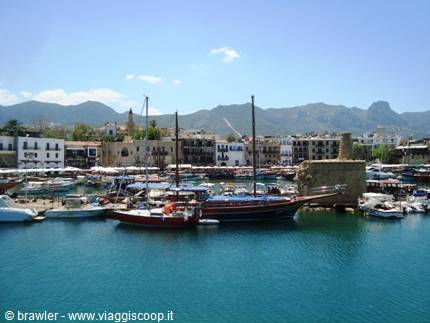 Wooden boats moored at Kyrenia harbour, colorful houses and mountains behind