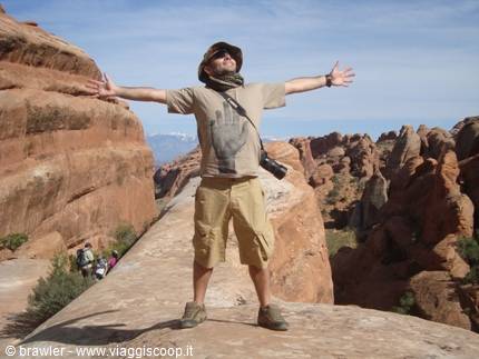 Tourist with open arms on the red sandstone fin at Arches National Park