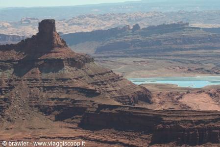 Canyonlands: red rock butte over layered canyons, turquoise ponds below