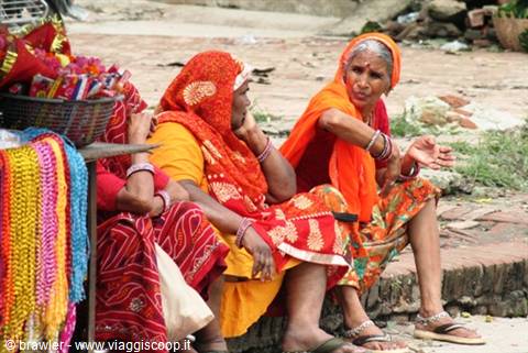 Indian women in colorful saris sitting beside a bead necklace stall