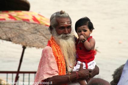 White-bearded sadhu holding a little girl on the Varanasi ghats