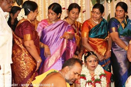 Bride wearing flower garlands with women in silk saris, Hindu wedding ceremony