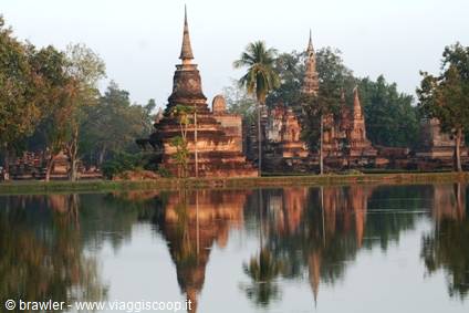 Ancient brick chedis of Sukhothai reflected in the lake at dawn