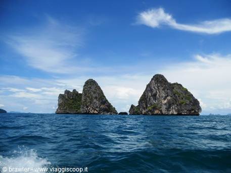 Limestone karst cliffs rising from the blue sea, seen from a moving boat