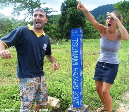 Two tourists mock panic beside the blue Tsunami Hazard Zone sign