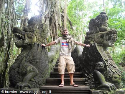 Smiling traveler standing on stone stairs between two dragon statues, Ubud Monkey Forest