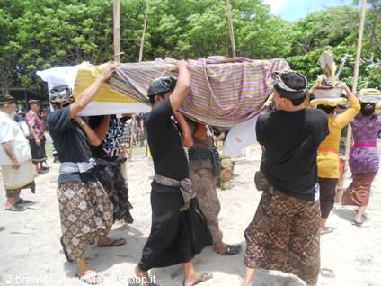 Men in Balinese sarongs carry a wrapped body during a traditional cremation ceremony