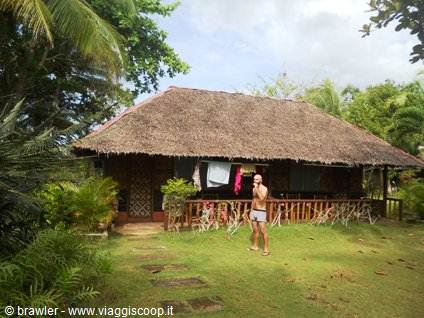Man in shorts standing outside a thatched wooden bungalow