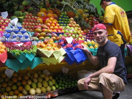 Man crouching in front of a colorful fruit stall at the market