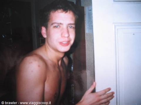 Shirtless young man beside a white door, harsh flash lighting