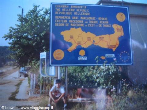 Boy sitting under a tourist sign of East Macedonia and Thrace