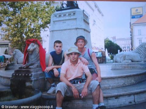 Three friends sitting on a lion fountain in a town square