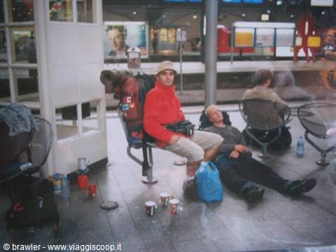 Traveler with backpack and red sweater waiting with a friend on a station bench