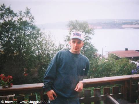 Young man in white cap on wooden terrace overlooking the fjord