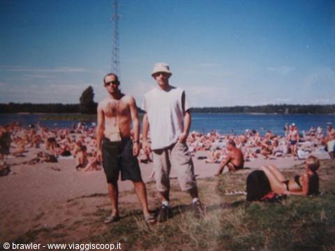 Two friends posing on crowded Hietaniemi beach, Helsinki, with sunbathers around