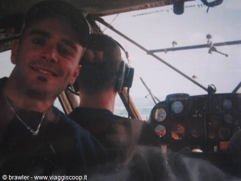 Smiling pilot inside small aircraft cockpit, instruments and sea visible