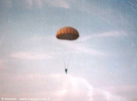 Parachutist descending with orange canopy in blue sky