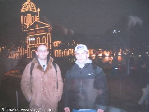Two young men in winter jackets at night before Montpellier's illuminated Opéra Comédie