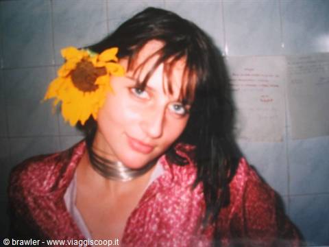 Girl with sunflower in hair and metal necklace, tiled wall