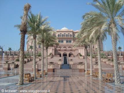 Emirates Palace in Abu Dhabi with palm trees and fountains along the entrance avenue