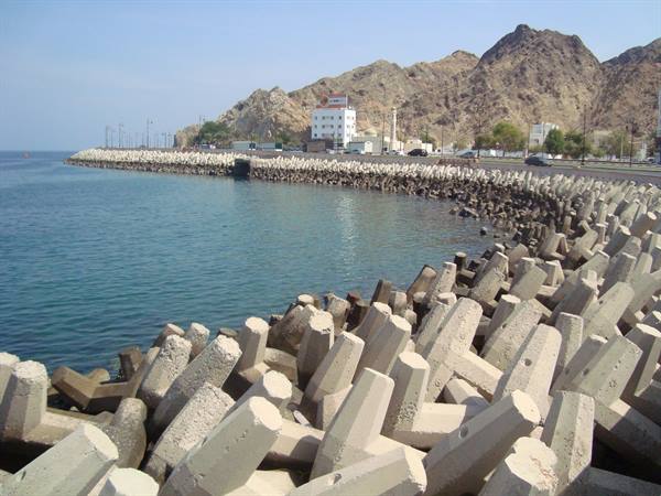 Tetrapod concrete breakwater along the coast beneath arid rocky mountains